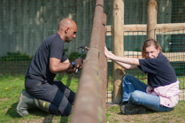 Young girl and man working on a fence outside