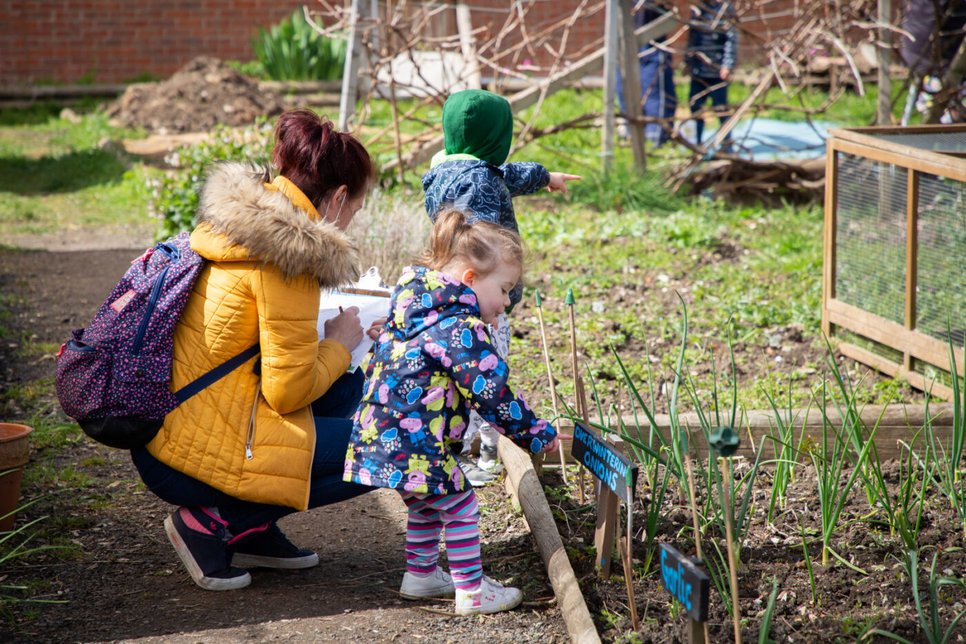 A mother crouched down with her two children, completing one of the trail activities at the allotment.