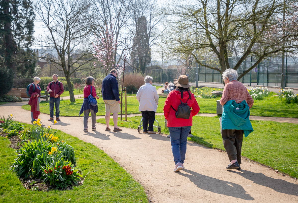 Group of people chatting and walking along a pathway in Stratford Park.