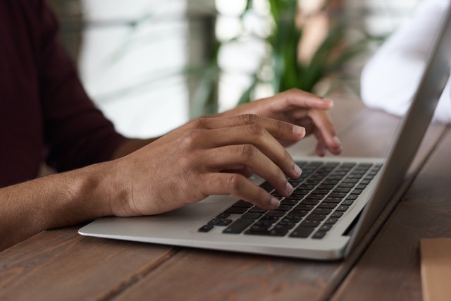 Close up shot of some hands typing on a laptop.