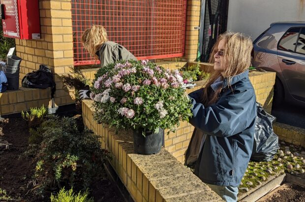 Two ladies preparing some flowers to be planted in a planter on Barton Street.