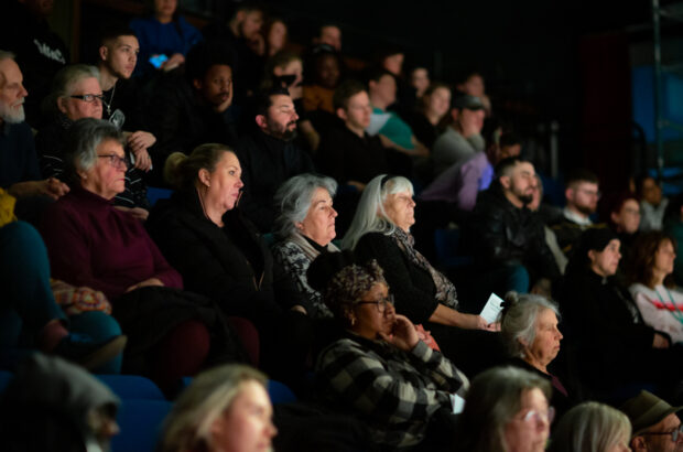 Crowd of people sat in elevated chairs, watching 