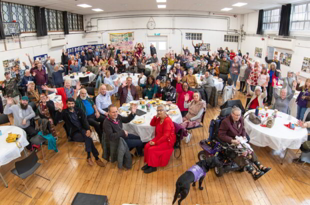 A wide shot of everyone in the hall at the party waving at the camera.