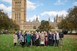A group photo of everyone who road a coach down to London to attend the Gloucester Services 10th Celebration. They're posing in the park outside the Houses of Parliament.