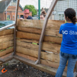 Rich and some people from Gloucester College putting wooden planks on a shelter frame.