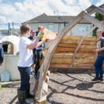 Young people fixing wooden planks to the frame of a shelter at our allotment.