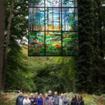 Group of people smiling happily under the 'Cathedral Window' at the Forest of Dean Sculpture Trail.