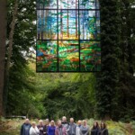 Group of people smiling happily under the 'Cathedral Window' at the Forest of Dean Sculpture Trail.