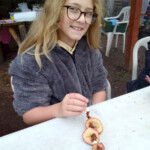 A young girl smiling as she shows off the bird feeder she made.