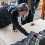 Young person leaning over a table with a wooden plank on it.