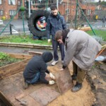 Three young people laying some paving in our allotment.