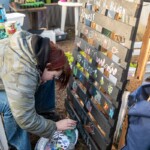 A young person painting some designs on a sign to advertise things at the allotment.