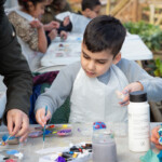 A child painting on the table instead of the pebble.