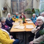 Group photo of Stroud participants sitting in a cafe, smiling at the camera.