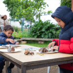 Two young boys sat at a table playing with clay.