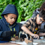 Two young boys, both working on their clay statuettes.