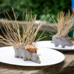 Two clay hedgehogs with straw used as spines coming out of their backs.