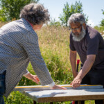 Ruth and Reyaz using a spirit measure to check a table is level before putting a hive on it.