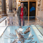 Rob standing at the end of a glass cabinet full of bones, smiling at camera.