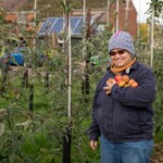 Participant smiling as she holds an armful of apples.