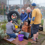 Group of Spirax Sarco volunteers discussing how best to build the brick BBQ.