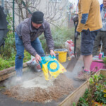 Spirax Sarco volunteer mixing cement to use to build a brick BBQ.