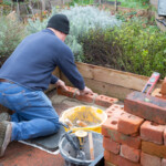 Spirax Sarco volunteer laying the base bricks for the BBQ.