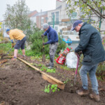 Three Spirax Sarco volunteers digging holes for posts to make a new plant bed border.