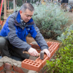 One of the Spirax Sarco volunteers hammering down a brick when building the BBQ.