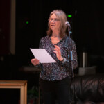 Sue standing behind a microphone and welcoming everyone to "On a Knife Edge".