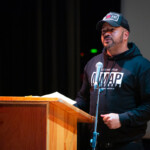 Mr. Milise reciting one of his spoken word poems behind a lectern.