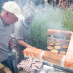 Reyaz and Gary tending to the BBQ and cooking burgers amongst a cloud of smoke.