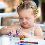 A young girl using some flowers to decorate her fairy.