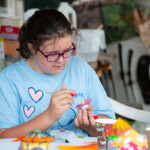 A young girl using a felt tip to decorate the fairy.