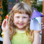 A young girl holding up her fairy and fairy house.