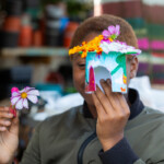A person holding the fairy house they made, decorated with felt tips and petals from flowers.