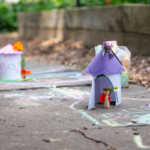 Some fairy houses made out of coloured card, placed on the path in the allotment.