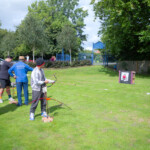 Two young men preparing to shoot at balloons attached to the archery targets.