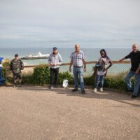 Group of participants standing along a fence, overlooking the beach and ocean.