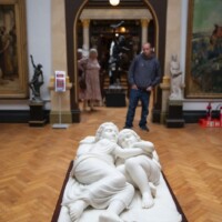A photo of a sculpture of two people in bed.