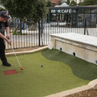 Jack hitting a golf ball, aiming for one of three holes going through a stone bench.