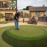 Gary hit a ball at an outdoor crazy golf course, but the ball went over the hole.