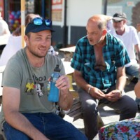 Group of participants sat on wooden benches on the seafront plaza.