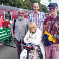 Reyaz with some participants smiling in front of a train.