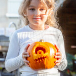 A young girl holding the carved cyclops pumpkin she helped design.