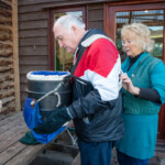 Chrissy helping put a picking basket on a participant, making sure the straps fit properly.