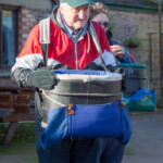 Male participant standing around, having successfully put his picking basket on.