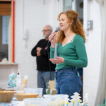 Katie standing behind the table, giving a speech.