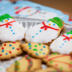 A close up photo of cookies. They've been iced to resemble snowmen and christmas trees.