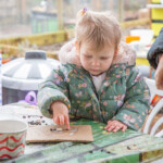A young child sticking beans onto a snail template.